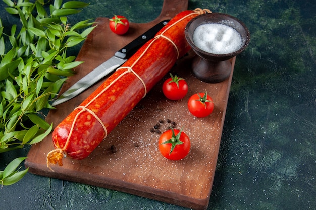 Vue de face de délicieuses saucisses fraîches avec des tomates sur un hamburger alimentaire bleu foncé repas sandwich aux animaux pain pain couleur viande