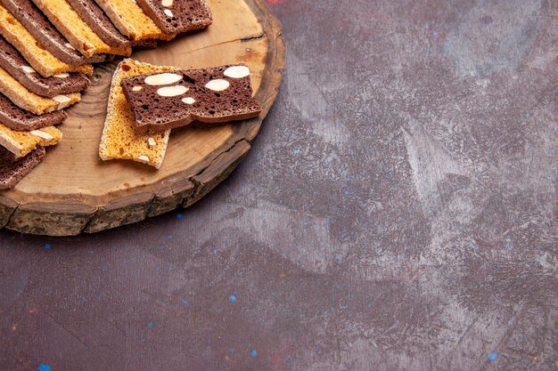 Vue de face de délicieuses tranches de gâteau aux noix sur un espace sombre