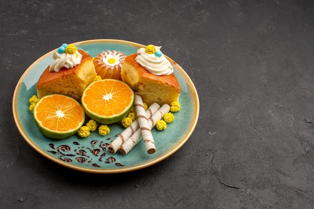 Vue de face de délicieuses tranches de gâteau avec des biscuits à la pipe et des mandarines tranchées sur un espace sombre