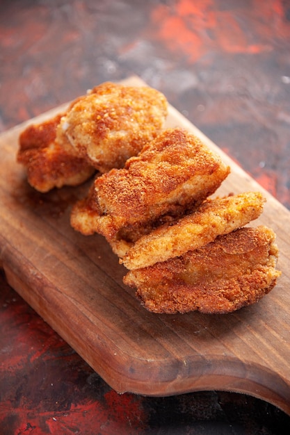 Vue de face de délicieux ailes de poulet sur une planche à découper fond sombre déjeuner dîner sandwich repas burger nourriture salade