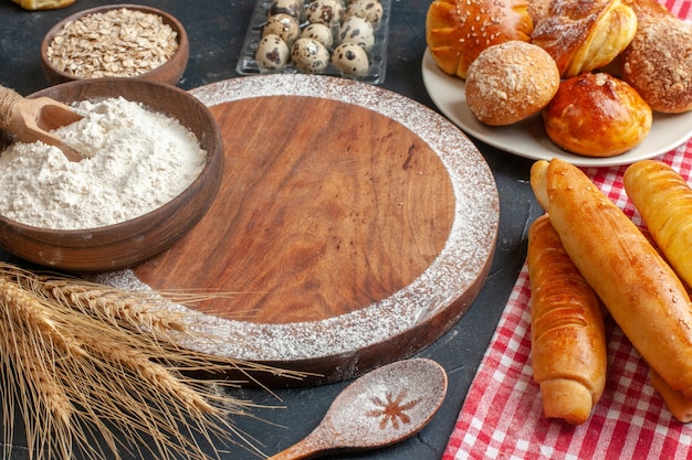 Vue de face de délicieux bagels sucrés avec des petits pains et de la farine sur un gâteau à la pâte à tarte à la pâtisserie noire au sucre