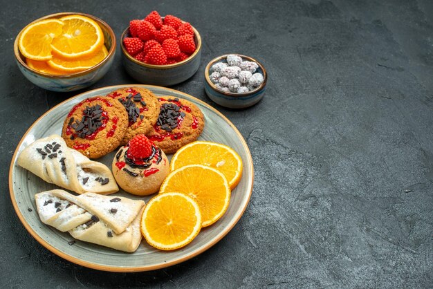 Vue de face de délicieux biscuits au sucre avec des pâtisseries et des tranches d'orange sur une surface sombre biscuit au sucre gâteau sucré thé aux biscuits