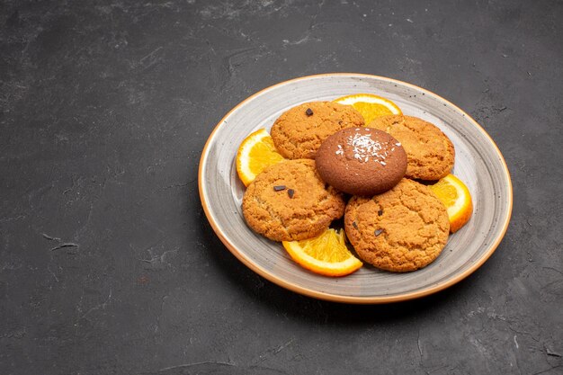 Vue de face de délicieux biscuits au sucre avec des tranches d'orange à l'intérieur de la plaque sur un bureau sombre biscuit au sucre aux fruits sucrés