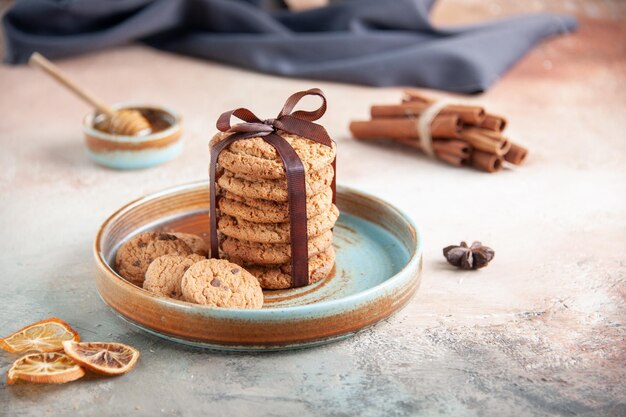 Vue de face de délicieux biscuits sucrés attachés avec un arc à l'intérieur de la plaque sur une surface légère de pâte à dessert, de thé de biscuit sucré, de gâteau horizontal