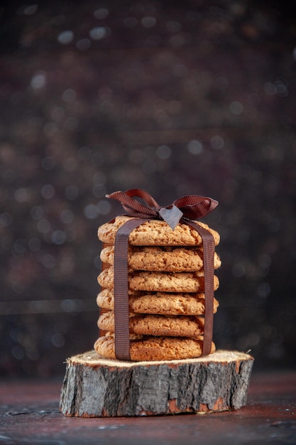 Photo gratuite vue de face de délicieux biscuits sucrés attachés avec un arc sur l'obscurité