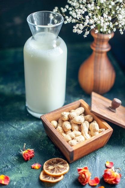 Vue de face de délicieux biscuits sucrés avec du lait et des noix sur la surface bleu foncé