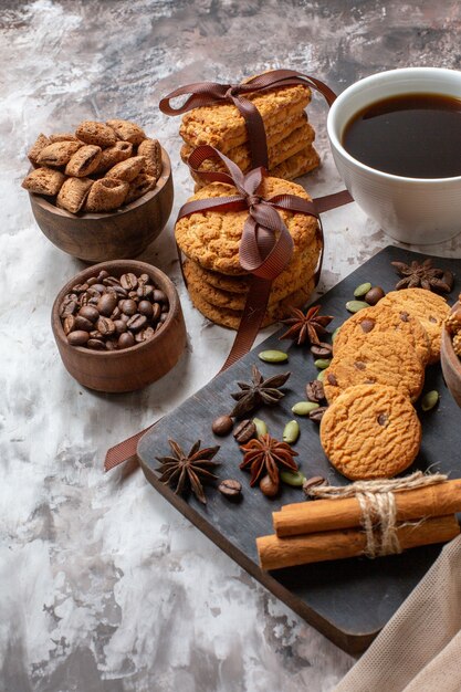 Vue de face de délicieux biscuits sucrés avec des graines de café et une tasse de café sur fond clair couleur cacao sucre biscuit au thé tarte au gâteau sucré
