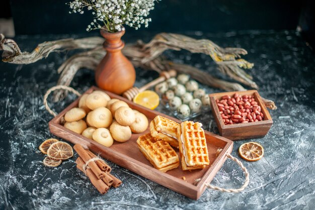 Vue de face de délicieux biscuits sucrés avec de petits gâteaux sur une surface gris clair