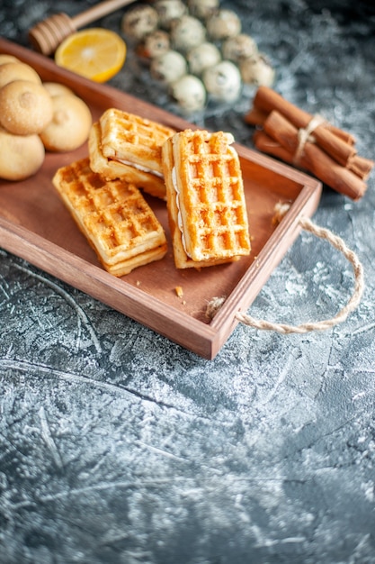 Vue de face de délicieux biscuits sucrés avec de petits gâteaux sur une tarte sucrée de couleur gris clair, un gâteau aux noix et aux biscuits au sucre