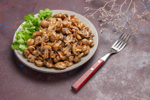 Vue de face de délicieux champignons cuits avec des verts sur un espace sombre