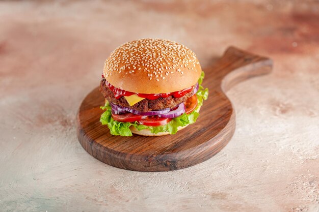 Vue de face d'un délicieux cheeseburger à la viande sur une surface claire de la planche à découper