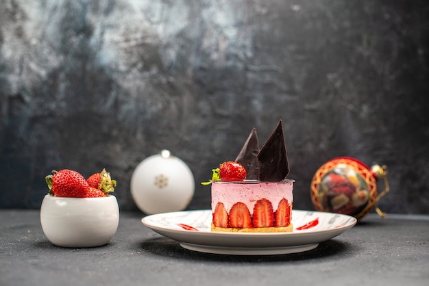 Vue de face délicieux cheesecake à la fraise et au chocolat sur une assiette ovale bol de fraises
