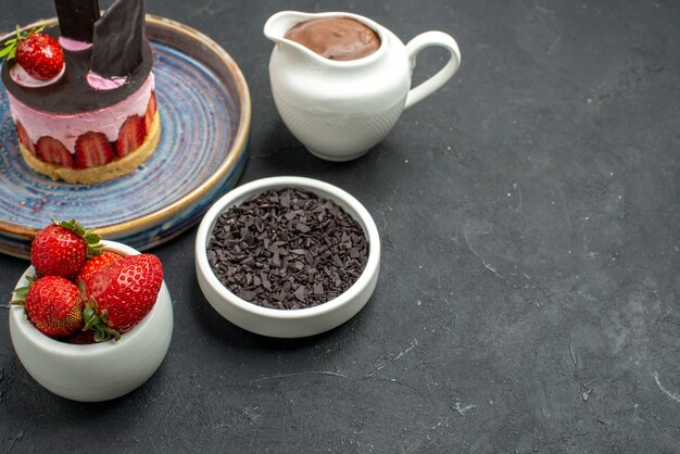 Vue de face délicieux cheesecake à la fraise et au chocolat sur des bols en assiette avec des fraises au chocolat chocolat noir sur fond noir isolé place libre