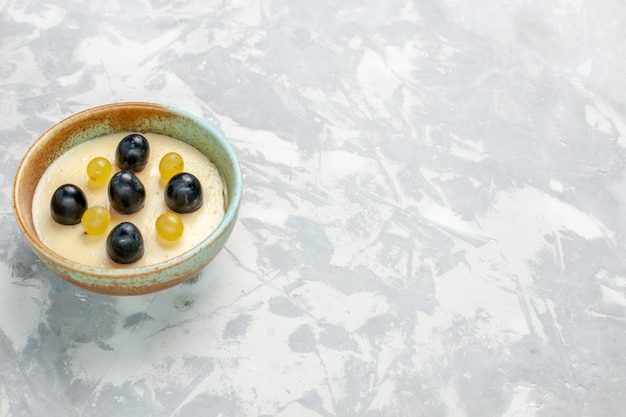 Photo gratuite vue de face délicieux dessert crémeux avec des fruits sur le dessus à l'intérieur du petit pot sur une surface blanche