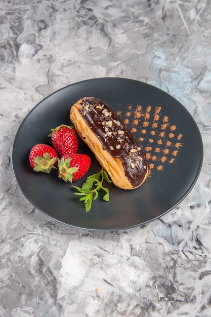 Vue De Face De Délicieux éclairs Au Chocolat Avec Des Fraises Sur La Table Lumineuse Des Bonbons Au Gâteau Au Dessert