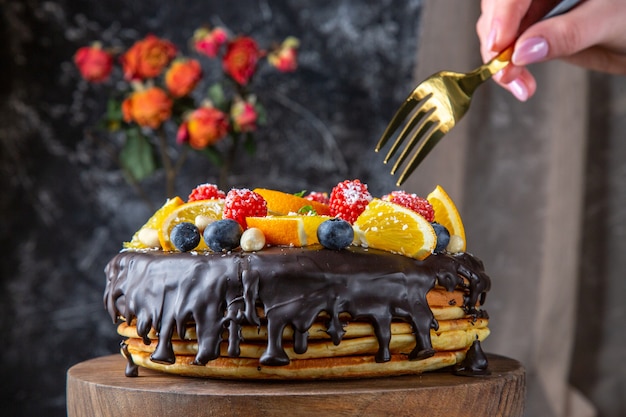 Vue de face délicieux gâteau au chocolat avec des fruits frais sur un mur sombre