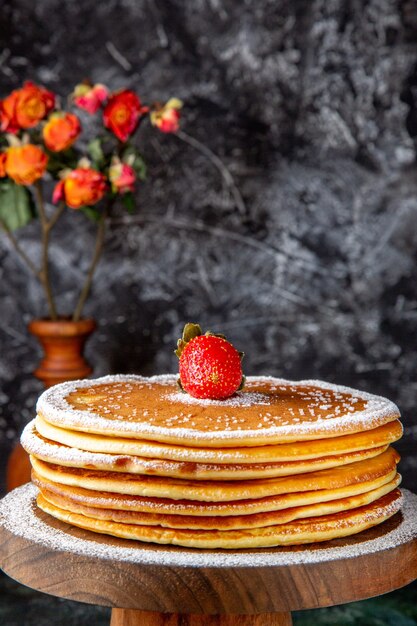 Vue de face délicieux gâteau au miel avec du sucre en poudre sur une surface sombre de planche de bois ronde