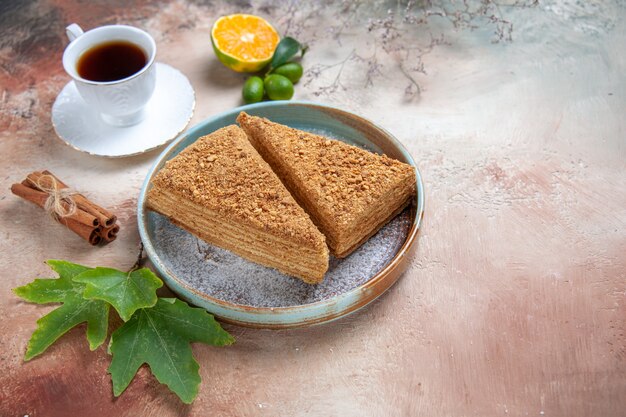 Vue de face délicieux gâteau au miel avec du thé à la lumière