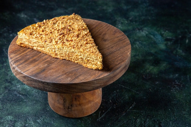 Vue de face de délicieux gâteau au miel tranche de celui-ci sur une surface sombre de planche de bois ronde