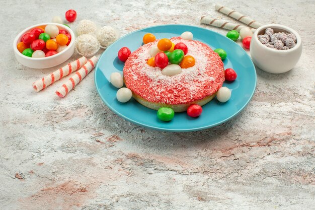 Vue de face délicieux gâteau rose avec des bonbons colorés sur fond blanc bonbons dessert couleur arc-en-ciel goodie cake