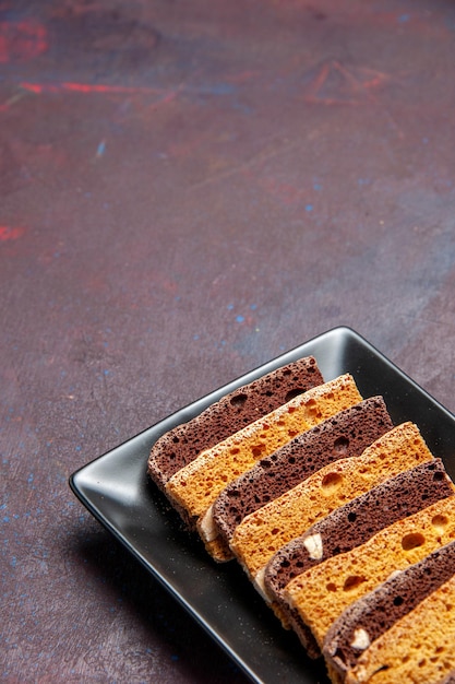 Vue de face délicieux gâteau en tranches avec des noix à l'intérieur du moule à gâteau sur un bureau sombre gâteau au thé sucré biscuit à la tarte au sucre