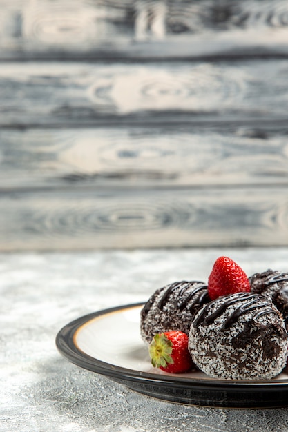 Vue de face de délicieux gâteaux au chocolat avec des fraises rouges fraîches sur la surface biscuit au sucre au chocolat gâteau sucré bake cookie