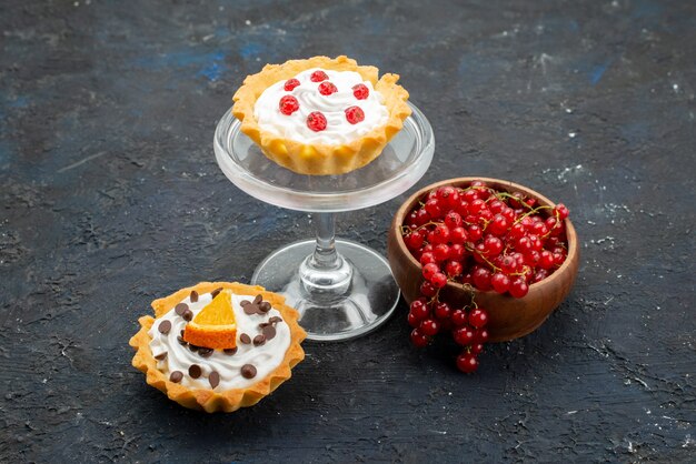 Photo gratuite vue de face de délicieux gâteaux à la crème et aux fruits sur la surface sombre douce