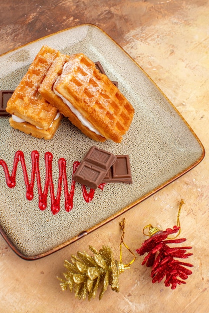 Photo gratuite vue de face de délicieux gâteaux à la gaufre avec des barres de chocolat sur fond marron