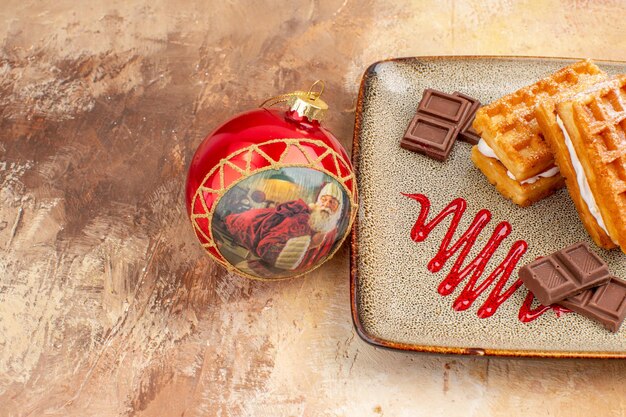 Vue de face de délicieux gâteaux à la gaufre avec des barres de chocolat sur fond marron