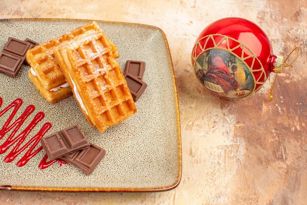 Vue de face de délicieux gâteaux à la gaufre avec des barres de chocolat sur fond marron