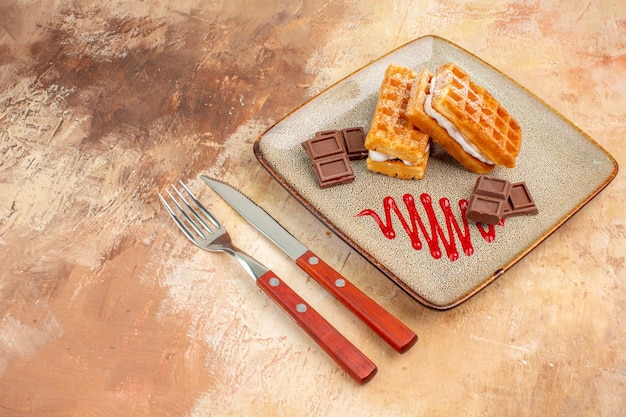 Vue de face de délicieux gâteaux à la gaufre avec des barres de chocolat sur fond marron