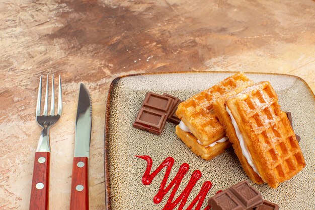 Vue de face de délicieux gâteaux à la gaufre avec des barres de chocolat sur un sol marron