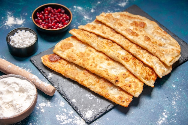 Vue de face de délicieux gutabs minces et délicieux petits gâteaux avec de la viande sur une surface bleue