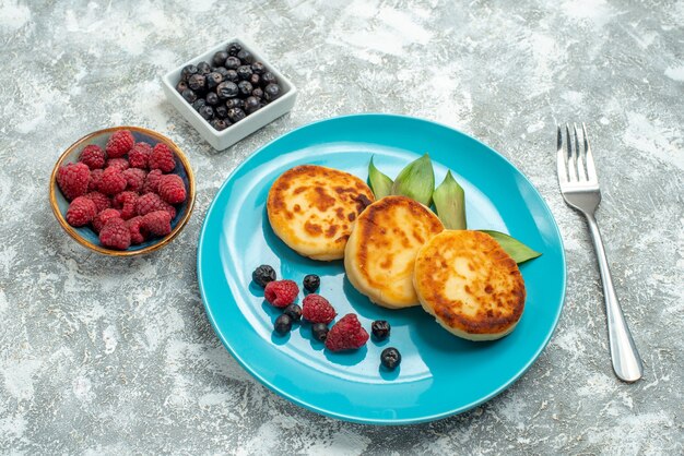 Vue de face de délicieux muffins aux baies sur une table lumineuse