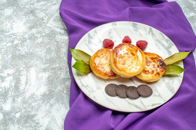 Vue de face de délicieux muffins avec des biscuits au chocolat sur une table lumineuse