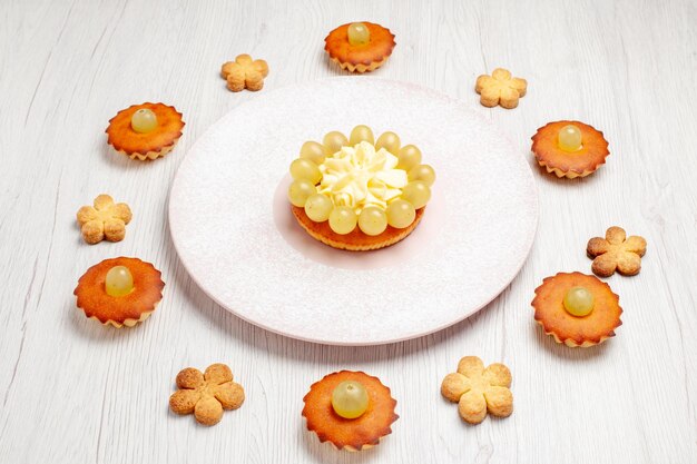 Vue de face de délicieux petits gâteaux bordés sur fond blanc dessert biscuit gâteau au thé tarte biscuit sucré