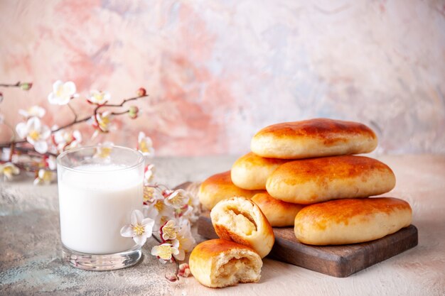 Vue de face de délicieux petits pains cuits au four avec un verre de lait