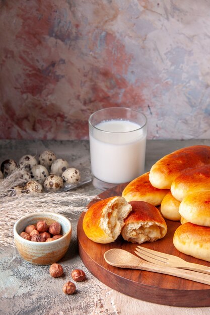 Vue de face de délicieux petits pains cuits au four avec un verre de lait