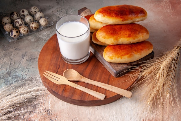 Vue de face de délicieux petits pains cuits au four avec un verre de lait