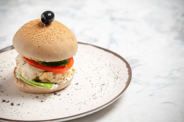 Vue de face d'un délicieux sandwich fait maison avec olive noire sur une assiette sur une surface blanche tachée avec espace libre