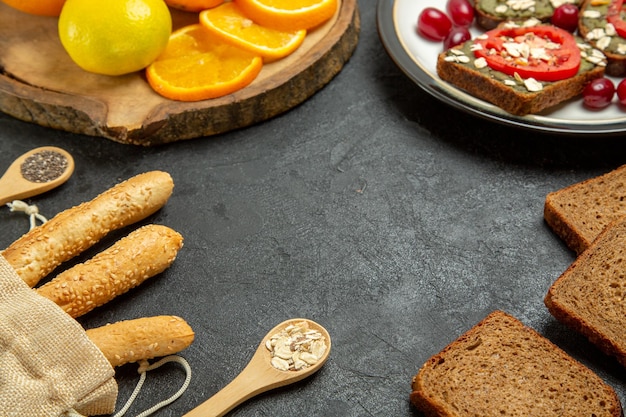 Vue de face de délicieux sandwiches à l'avocat avec des oranges fraîches sur une surface grise