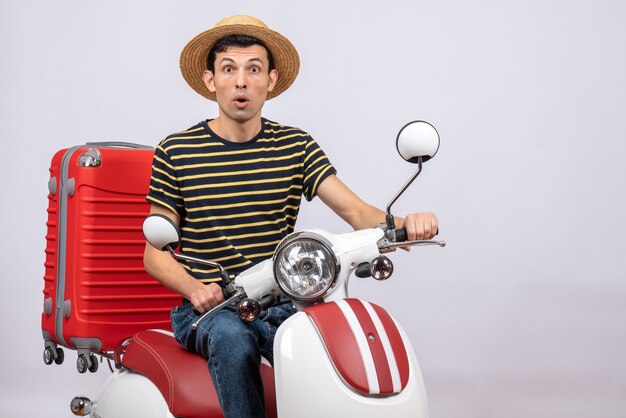 Vue de face demandé jeune homme avec chapeau de paille sur cyclomoteur regardant la caméra