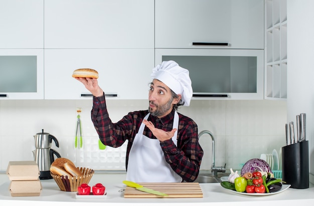 Photo gratuite vue de face dérouté chef masculin brandissant du pain dans la cuisine