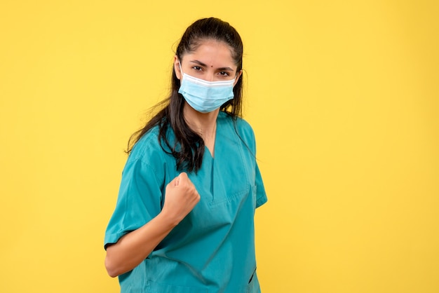 Photo gratuite vue de face déterminée femme médecin montrant son coup de poing sur fond jaune