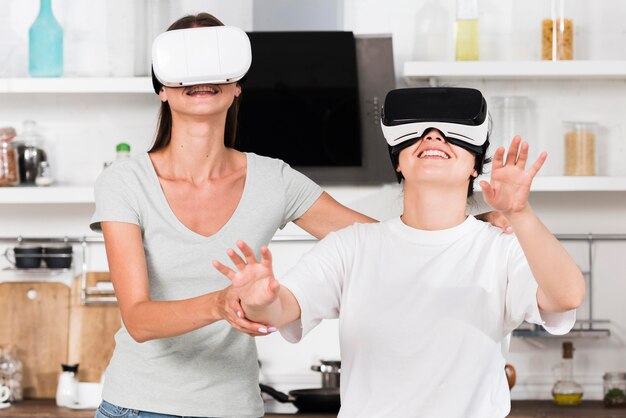 Vue de face de deux amis à la maison s'amusant avec un casque de réalité virtuelle