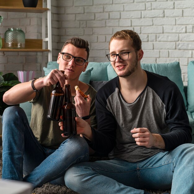 Vue de face de deux amis masculins à regarder les sports à la télévision et à boire de la bière