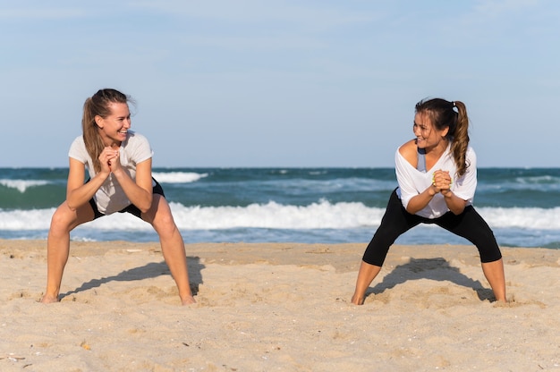 Vue de face de deux femmes exerçant sur la plage