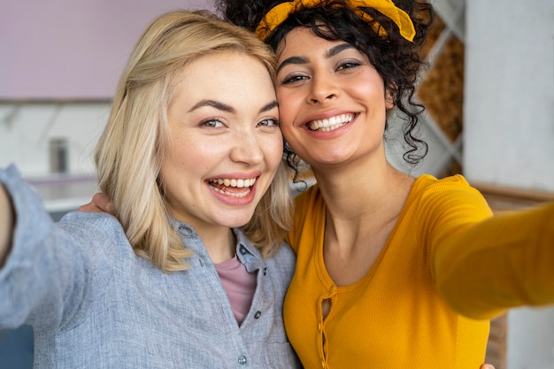 Vue de face de deux femmes souriantes prenant un selfie