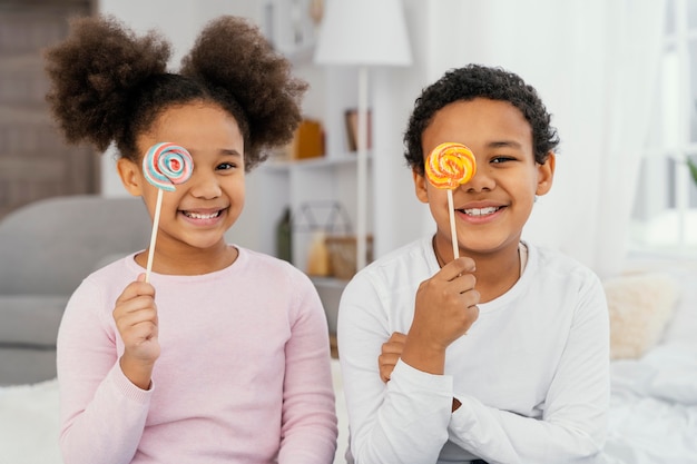 Photo gratuite vue de face de deux frères et sœurs smiley posant avec des sucettes