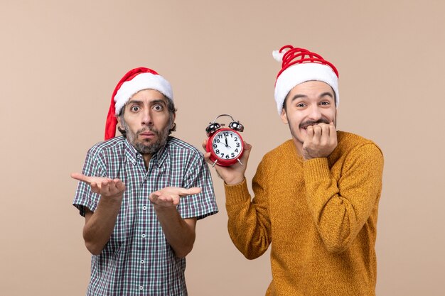 Vue de face deux hommes un confus et un heureux tenant un réveil sur fond isolé beige